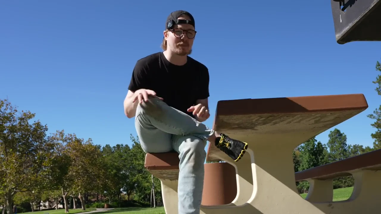 Seated figure-four glute stretch demonstrated on a park bench