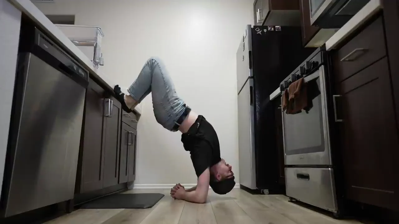 Advanced inverted wall-supported lat stretch demonstrated in the source