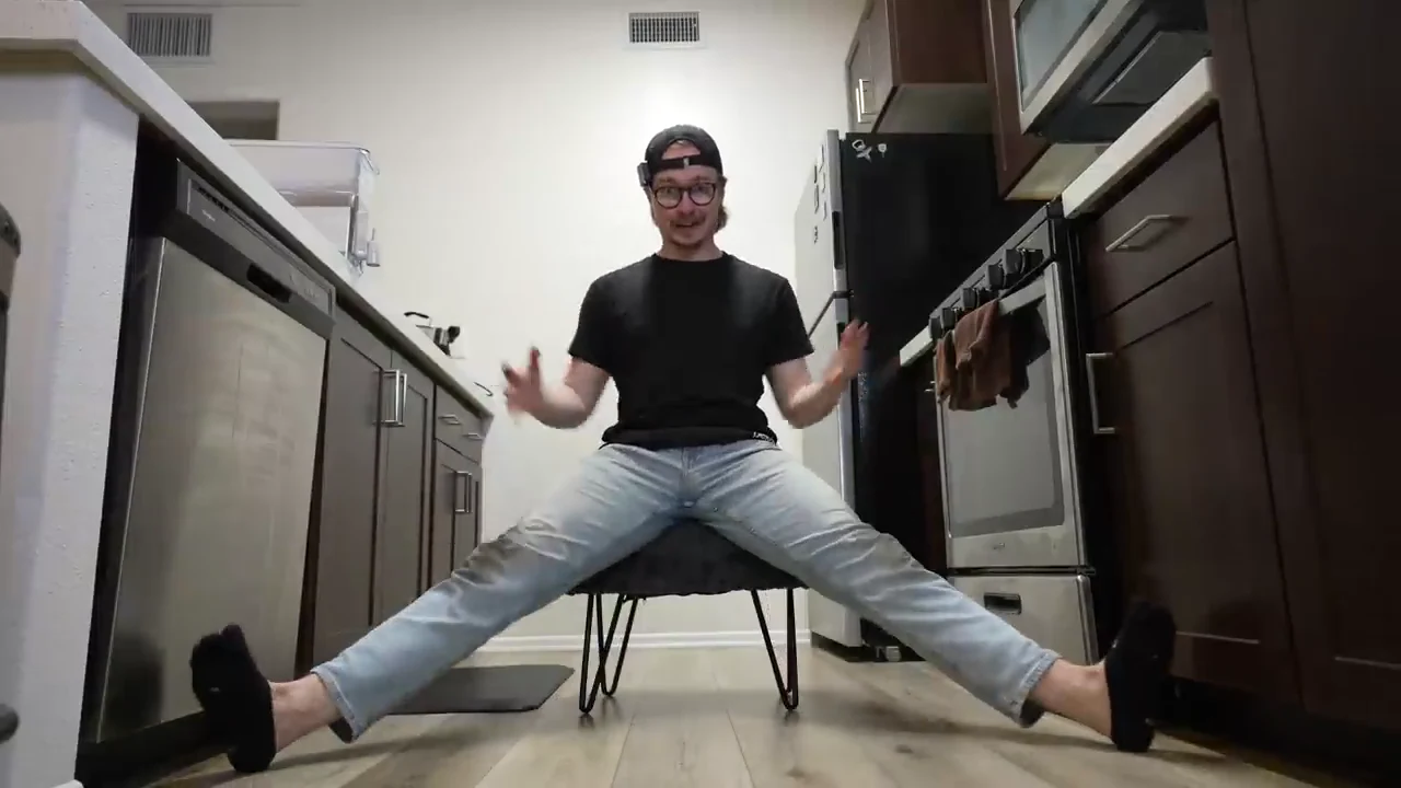 Elevated pancake stretch with David seated on a chair in a wide straddle