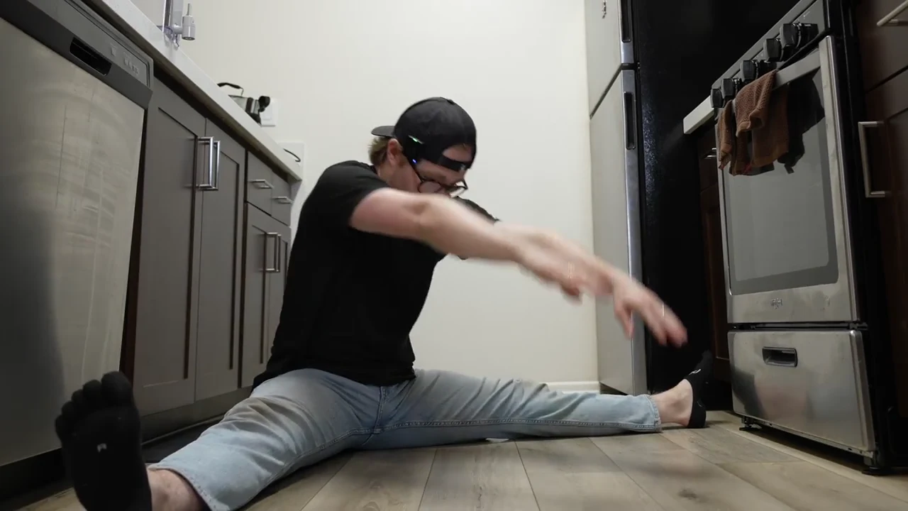 Floor pancake stretch with David reaching forward between wide legs